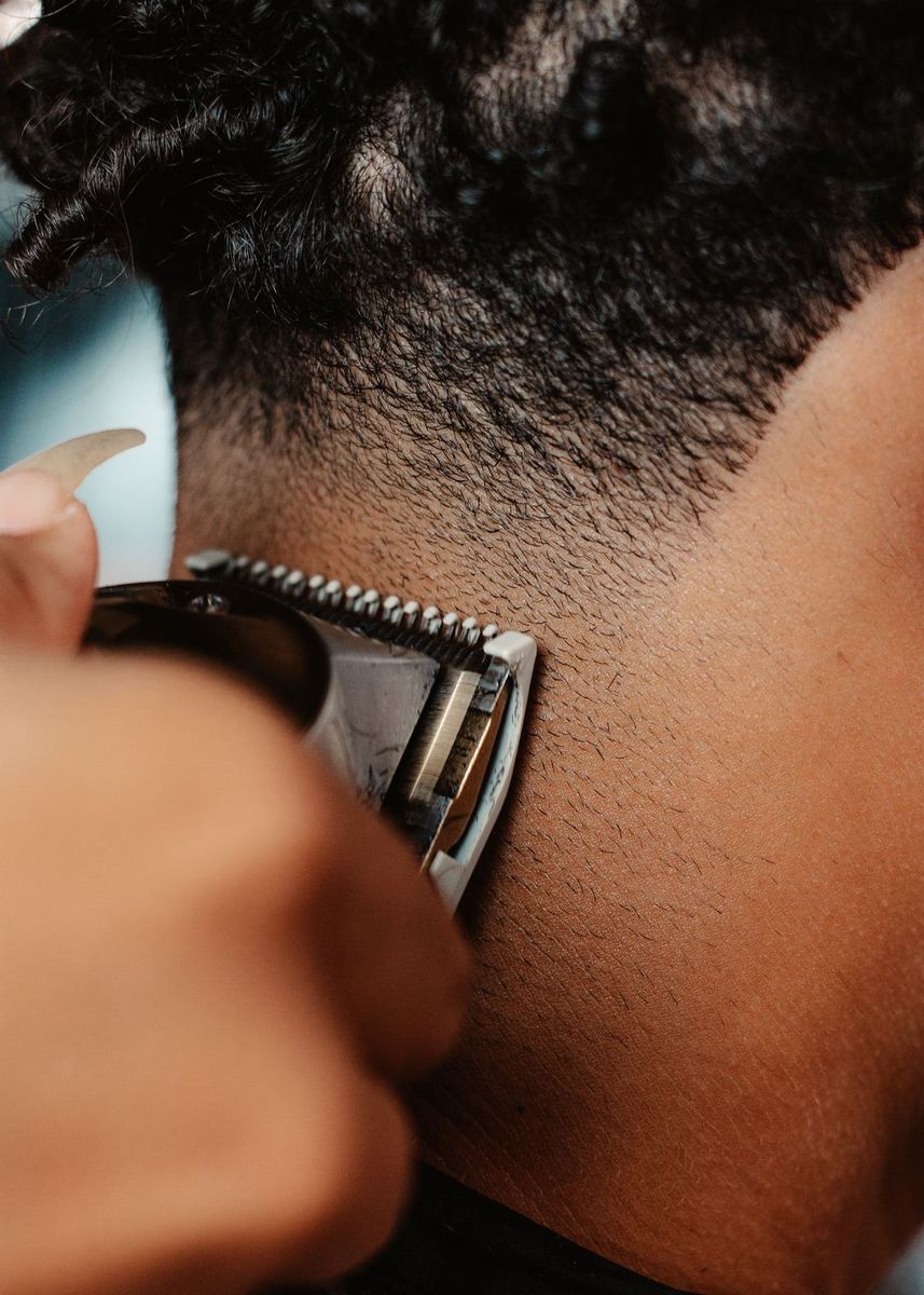 Barber running clippers through a mid fade, client facing away