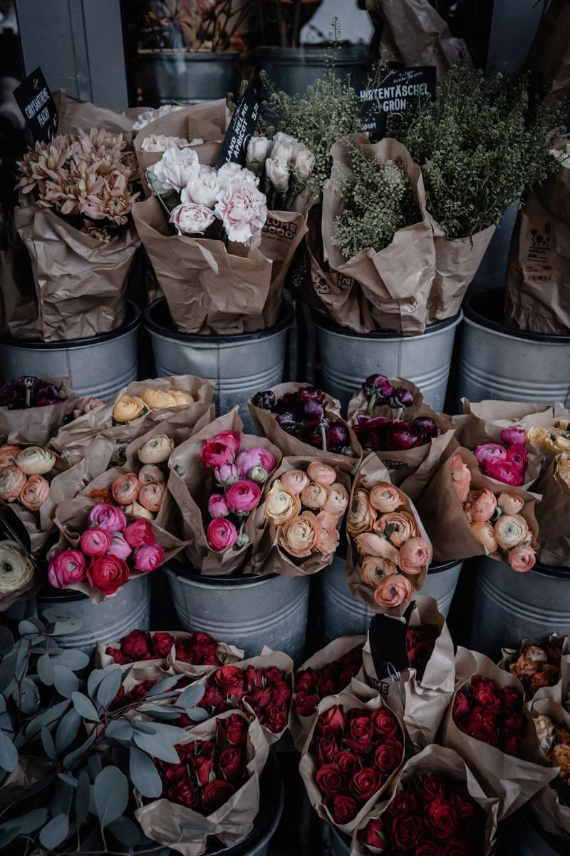Metal buckets of fresh cut stems lined up along the flower cooler wall