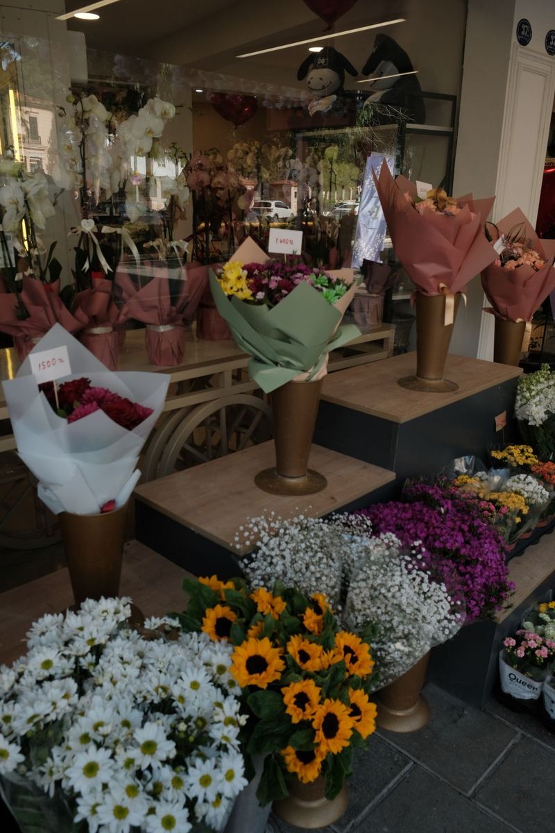 Flower shop storefront with paned windows and buckets of blooms by the door