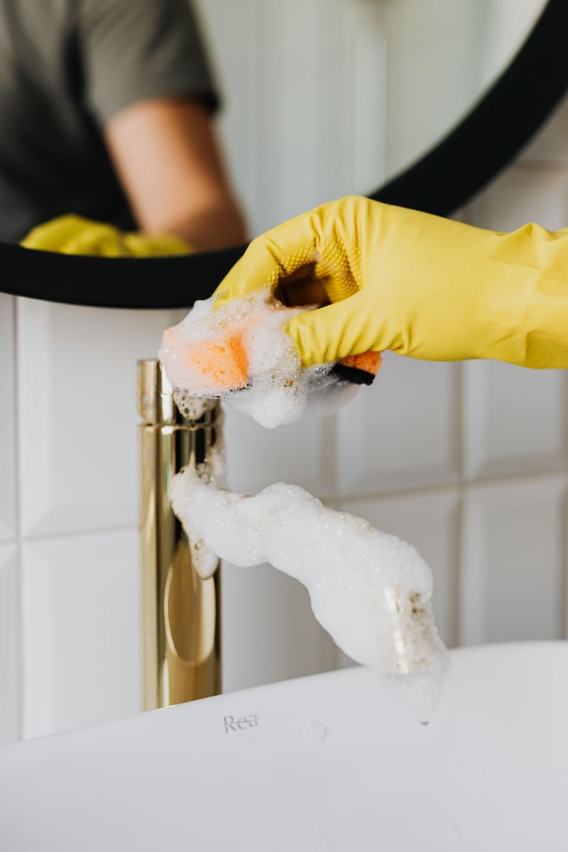 A gloved hand polishing a shining bathroom faucet