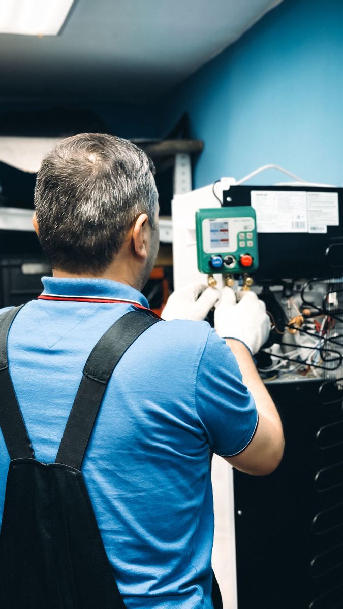Technician working on indoor heating equipment with a gauge manifold connected to the unit